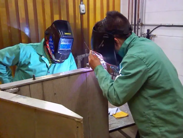 welding apprentice practicing under guidance from the welding school teacher